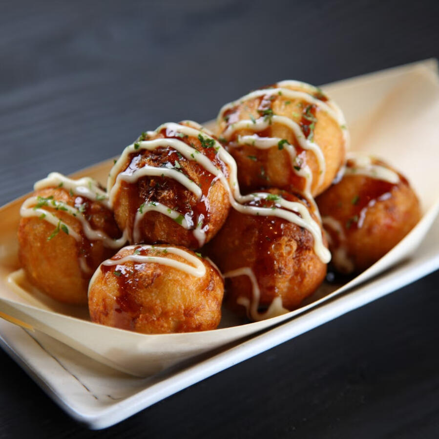 Takoyaki Bite-sized balls of fried pastry each containing a solitary chunk of tender octopus in their gooey, molten centers.