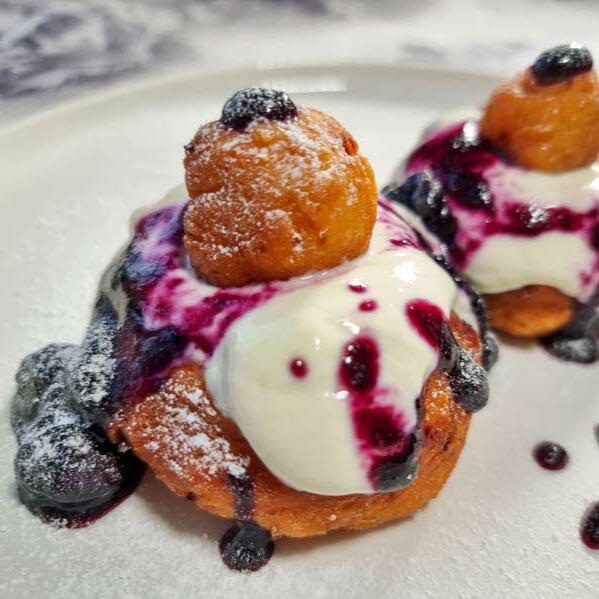 Papanasi Thick dough kneaded with soft cheese and fried into a hearty donut, slathered with yet more creamy cheese and a sweet-and-tart berry sauce.